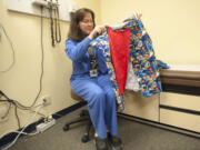 Charge nurse Carolyn Wynne shows off a superhero-themed gown she helped create for children who have to undergo physical exams through the Child Abuse Assessment Team.