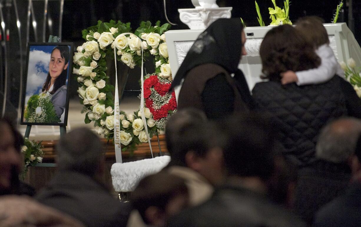 Women look inside Irina Gardinant's casket during the memorial service for her and Raisa Mosh.