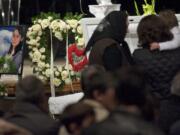 Women look inside Irina Gardinant's casket during the memorial service for her and Raisa Mosh.