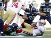 San Francisco 49ers quarterback Colin Kaepernick is sacked by Seattle Seahawks defensive tackle Jordan Hill (97) and outside linebacker K.J. Wright (50) in the first half against the Seattle Seahawks, Sunday, Dec.