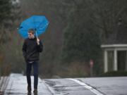 A gust of wind flips Spencer Henry's umbrella up as he walks west on Evergreen Boulevard over Interstate 5 on his way to work Tuesday. A continuing series of storms brought more than a half inch of additional rain, following an inch of rain that fell Monday. Wind gusts were measured as high as 28 mph at Pearson Field. Localized problems, such as flooded streets, were reported.