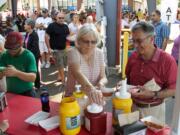 Liz and Raif Zacca of Vancouver get condiments for their sausages at the Vancouver Sausage Fest on Sunday. The two attend St.