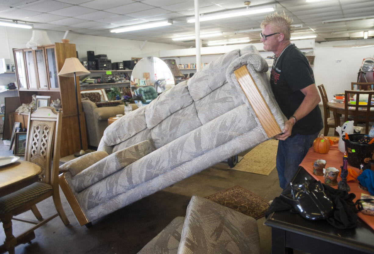 Employee Billy Peck arranges furniture for sale at Xchange Thrift Store in Vancouver.