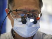 Dentist Eugene Sakai works on a patient in the Free Clinic of Southwest Washington's dental van Friday.