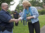 Open-carry gun activist Larry White and gun safety advocate and Vancouver City Councilwoman Anne McEnerny-Ogle shake hands as the two groups hold their separate rallies at Esther Short Park on Tuesday. McEnerny-Ogle was one of the few people who crossed camps to interact with the other group.