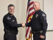 Vancouver Police Chief James McElvain, left, and Cpl. Aaron Gibson pose for a picture after Gibson's promotion ceremony Friday at the department's west precinct. Gibson was fired in 1997 for leaving explosives behind at a training site, but won his job back through arbitration.