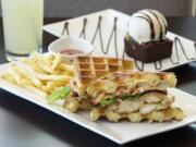 Luxe's chicken and waffle sandwich is stacked with greens, Gruy?re cheese, bacon, tomato and breaded chicken.