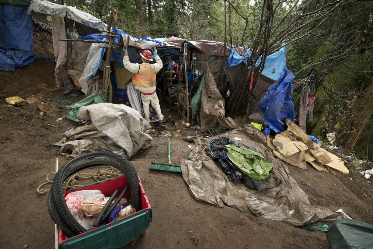 A crew member from the Larch Corrections Center begins tearing down a homeless camp in March in Hazel Dell.