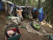 A crew member from the Larch Corrections Center begins tearing down a homeless camp in March in Hazel Dell.