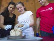 Liya Taziyeba, left, and Vicki Tolmachva, center, react as they hold a human brain under the supervision of Jeff Leake, right, an adjunct instructor, at an open house to celebrate the 25th anniversary of WSU Vancouver.