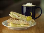 A ghiotto panino, made with bacon, chicken, avocado dressing and havarti cheese, and a black-and-white mocha are available to order at Coffee Villa in Vancouver.