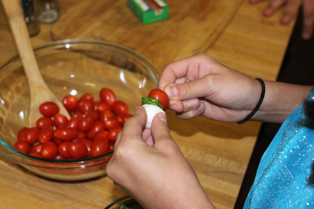 Jennifer Jorgensen
A Sunset Elementary School fifth-grader makes a salad skewer at a book release party Tuesday for &quot;The Cultured Chef: An International Cookbook for Kids.&quot; Teacher Rachelle Matheson helped create the book.