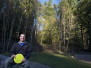 Mike Nemeth, who serves on Ridgefield's parks board and is the project lead in efforts to develop a disc golf course at Ridgefield's Abrams Park, sits near the wooded embankment where the course is proposed.