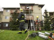 Firefighters clean up after a fire damaged an apartment complex at the Bridge Creek apartments on Sunday in Hazel Dell.