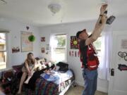 Red Cross volunteer Jeff Kuter installs a smoke alarm in Haven Reinhart's room Saturday.