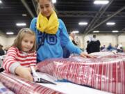 Alina Kiselev, 6, and her aunt Olya Bogush wrap a toy during the Santa's Posse gift wrapping night at the Clark County Event Center.