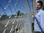 Andrew Tuttle, owner of Main Street Bar in Battle Ground, on Monday shows the tight clearance between the side of his business and a city fence.