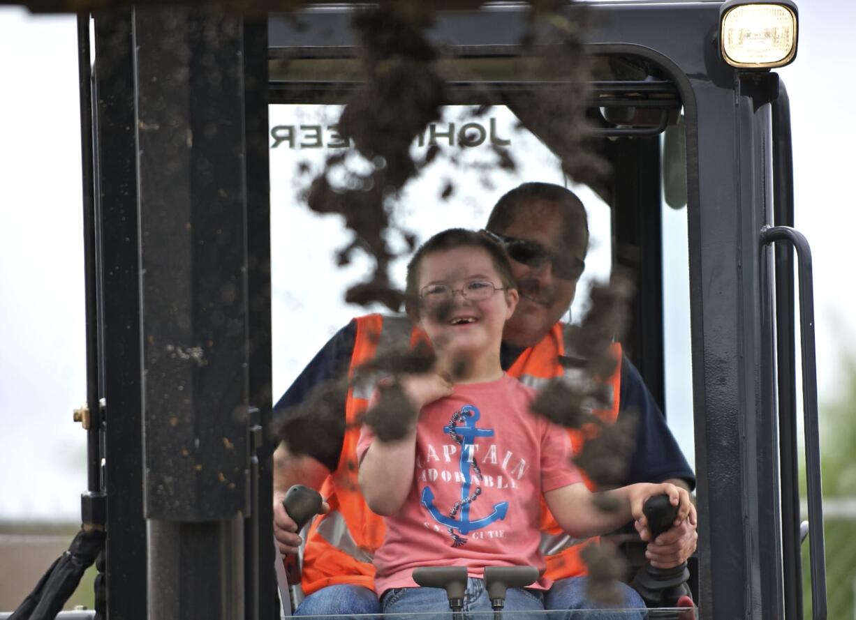 Pioneer Elementary first-grader Gage Figueroa, 7, gets a lesson on scooping and dumping dirt from Nutter Corporation equipment operator Jeff Bullinger.