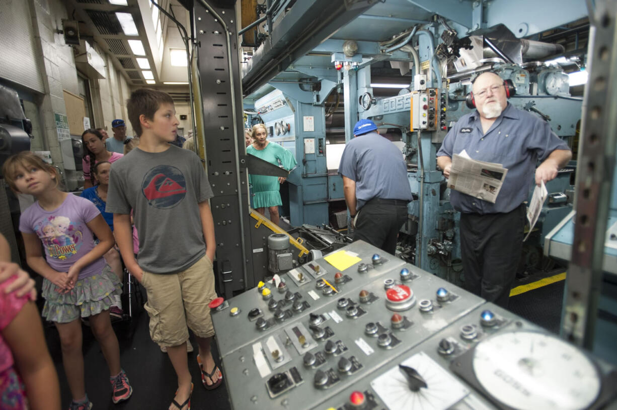 Charlie Elmlinger, right, mans the press as visitors stream past on a tour of The Columbian newspaper in Vancouver on Saturday . The event was held in advance of the Columbian newspaper's 125th anniversary, coming up in October.