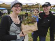 Wendy Galliart, left, and Molly Heikkinen, holding Louie, check out the plants at May 3 event to kick off a public market in Hazel Dell.