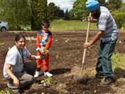 Harpal Kaur, left, preschooler Satraj Singh and Lakhbinder Singh help plant a new community garden on May 10 at Orchards Elementary School. Along with the family, nearly 200 other volunteers came out to clean up the property by the school's parking lot, which will now be used as an outdoor classroom and community garden.