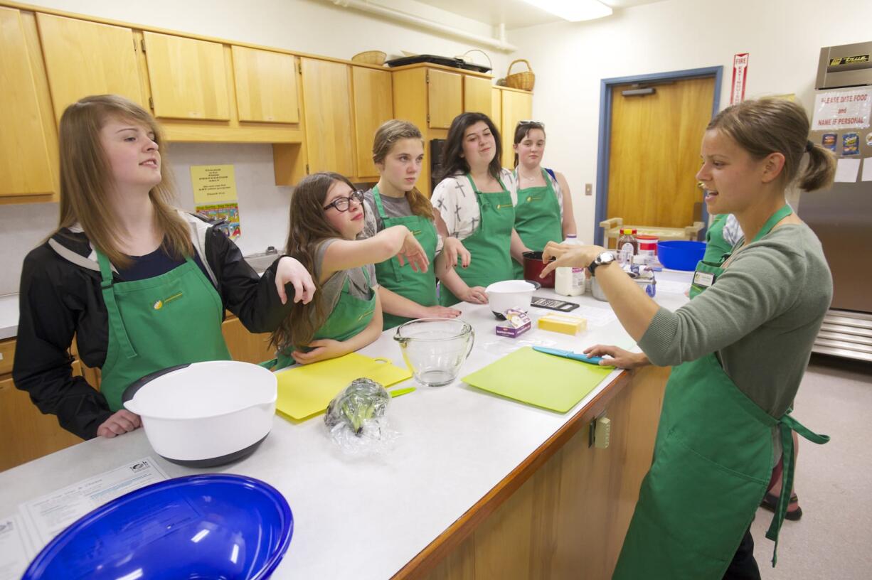 Xanna Burg from the Clark County Food Bank, right, on Tuesday teaches students how to use a &quot;bear claw&quot; to avoid cutting themselves while chopping fruits and vegetables.