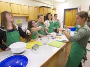 Xanna Burg from the Clark County Food Bank, right, on Tuesday teaches students how to use a &quot;bear claw&quot; to avoid cutting themselves while chopping fruits and vegetables.