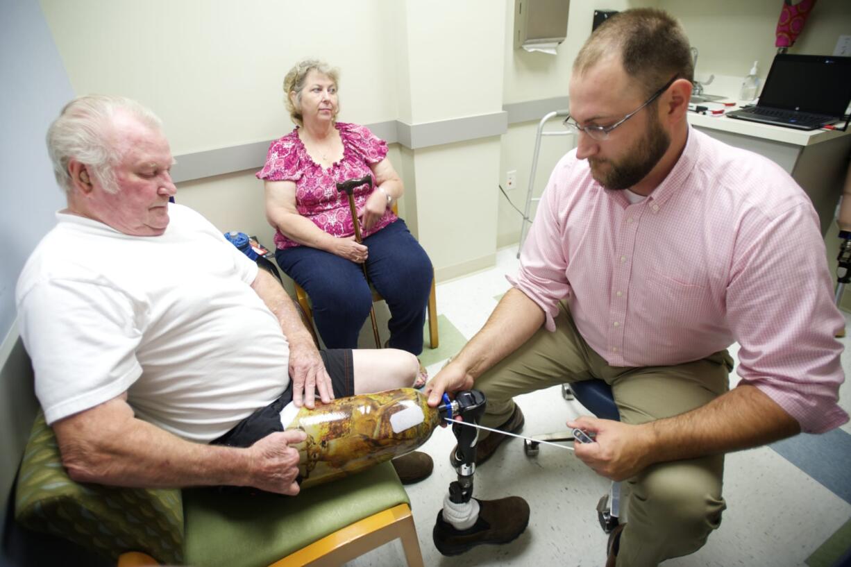 Mark Sauser, from Evergreen Prosthetics and Orthotics, makes adjustments Aug.