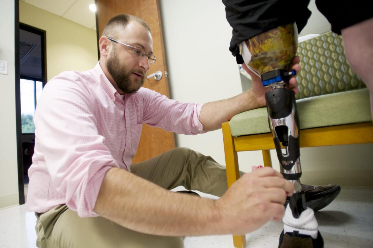 Mark Sauser, from Evergreen Prosthetics and Orthotics, makes adjustments to Earl Davidson's new prosthetic leg, Aug.