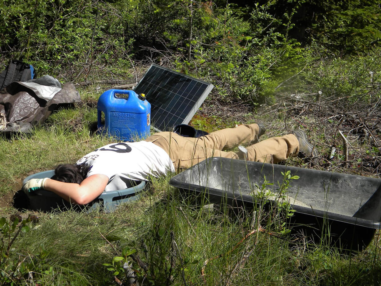 Kelley Hall, University of Washington graduate student, reaches down to do the final touches at the bottom of the seismometer site.