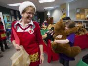 Fifth-grader Amy Shook hugs a stuffed bear as volunteer Renee Rhyasen helps her shop for gifts at Washington Elementary on Thursday.