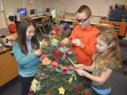 Washougal: Cape Horn-Skye Elementary School third-graders Ellison Wilkins, from left, Holden Bea and Avery Berg decorate a Christmas tree with paper ornaments with inspirational quotes for their classes holiday project.