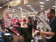 Band Director Tim Heichelheim, right, plays Christmas songs with a group of his students from Skyview High School on Saturday at the Salmon Creek Fred Meyer.