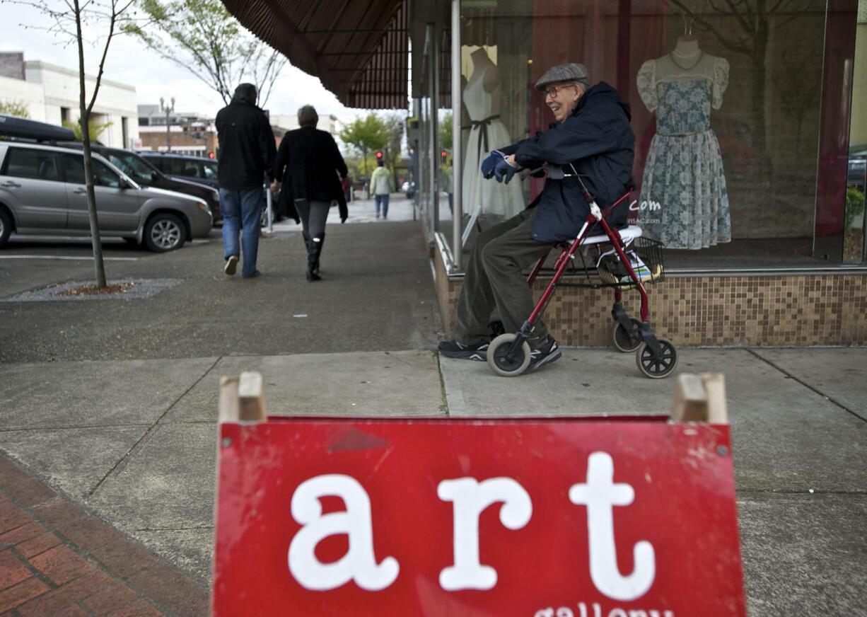 Painter and Southwest Washington Watercolor Society member John Beckman, 86, waits for a ride near a sign directing people to Gallery 360 at Main and Ninth streets during First Friday Downtown art walk.