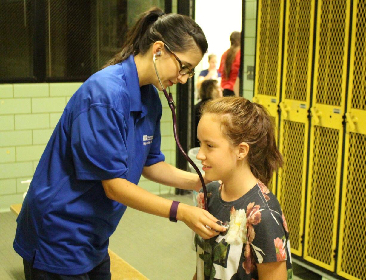 Central Park: PeaceHealth family medicine resident Lisa Cuneo examines 13-year-old volleyball and track athlete Jasmine Monagon.