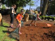 Nevaeh Jackson, right, Cherakee Elliott, left, and Oddessa Riley rake bark dust Saturday as part of a cleanup of Esther Short Park.