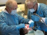 Drs. Glen Holler, left, and Gary Waldron provide dental care to Dana Duback de Sanchez at Battle Ground HealthCare Dental Clinic on in 2015.