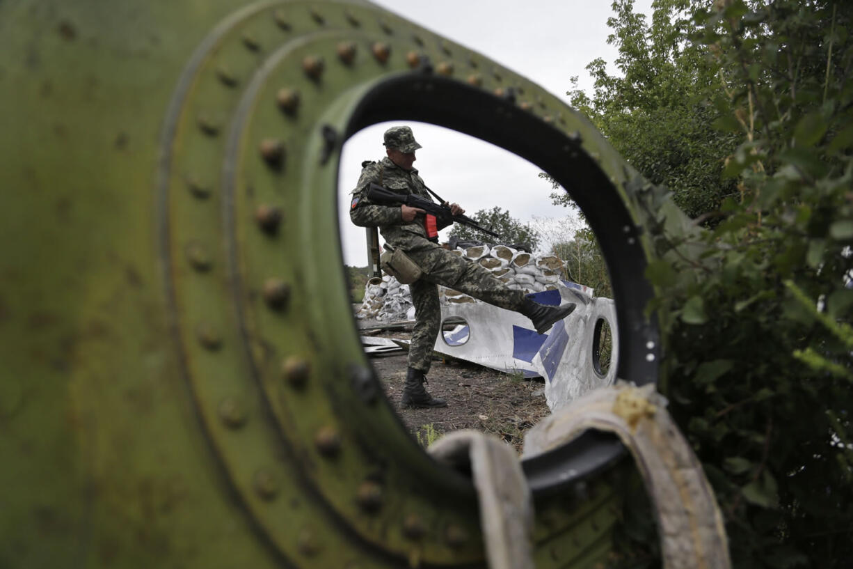 A Pro-Russian rebel looks at pieces of the Malaysia Airlines Flight 17 plane near village of Rozsypne, eastern Ukraine, on Tuesday.