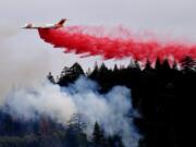 A firefighting plane drops a load of fire retardant over a smoldering hillside Tuesday in Middletown, Calif. The fire that sped through Middletown and other parts of rural Lake County, less than 100 miles north of San Francisco, has continued to burn since Saturday despite a massive firefighting effort.