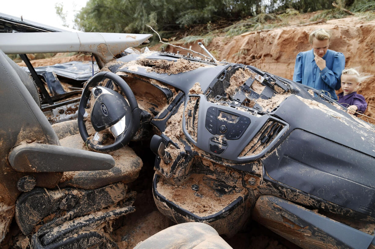 A woman and child examine a vehicle swept away during a flash flood Tuesday in Hilldale, Utah. Authorities say several people have died in flash flooding that swept away vehicles on the Utah-Arizona border.