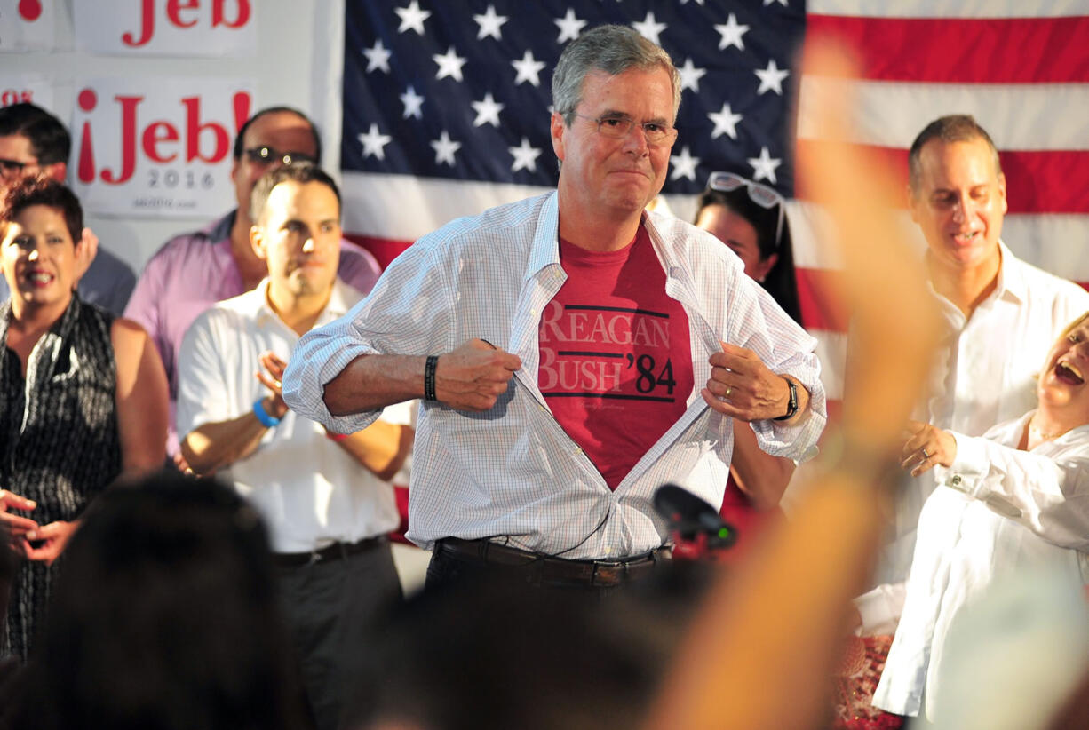 Republican presidential candidate and former Florida Gov. Jeb Bush shows off a Reagan/Bush '84 T-shirt as he speaks during the opening of his Miami campaign office Saturday in Miami.