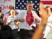 Republican presidential candidate and former Florida Gov. Jeb Bush shows off a Reagan/Bush '84 T-shirt as he speaks during the opening of his Miami campaign office Saturday in Miami.