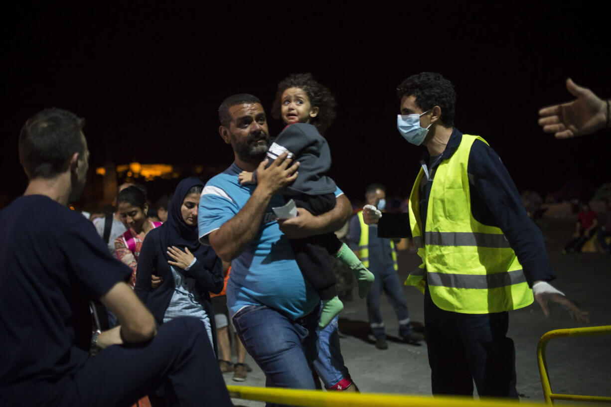 A Syrian man and his child board a ferry traveling to Athens, at the port of Lesbos Island, Greece, on Monday. The island of some 100,000 residents has been transformed by the sudden new population of some 20,000 refugees and migrants, mostly from Syria, Iraq and Afghanistan.