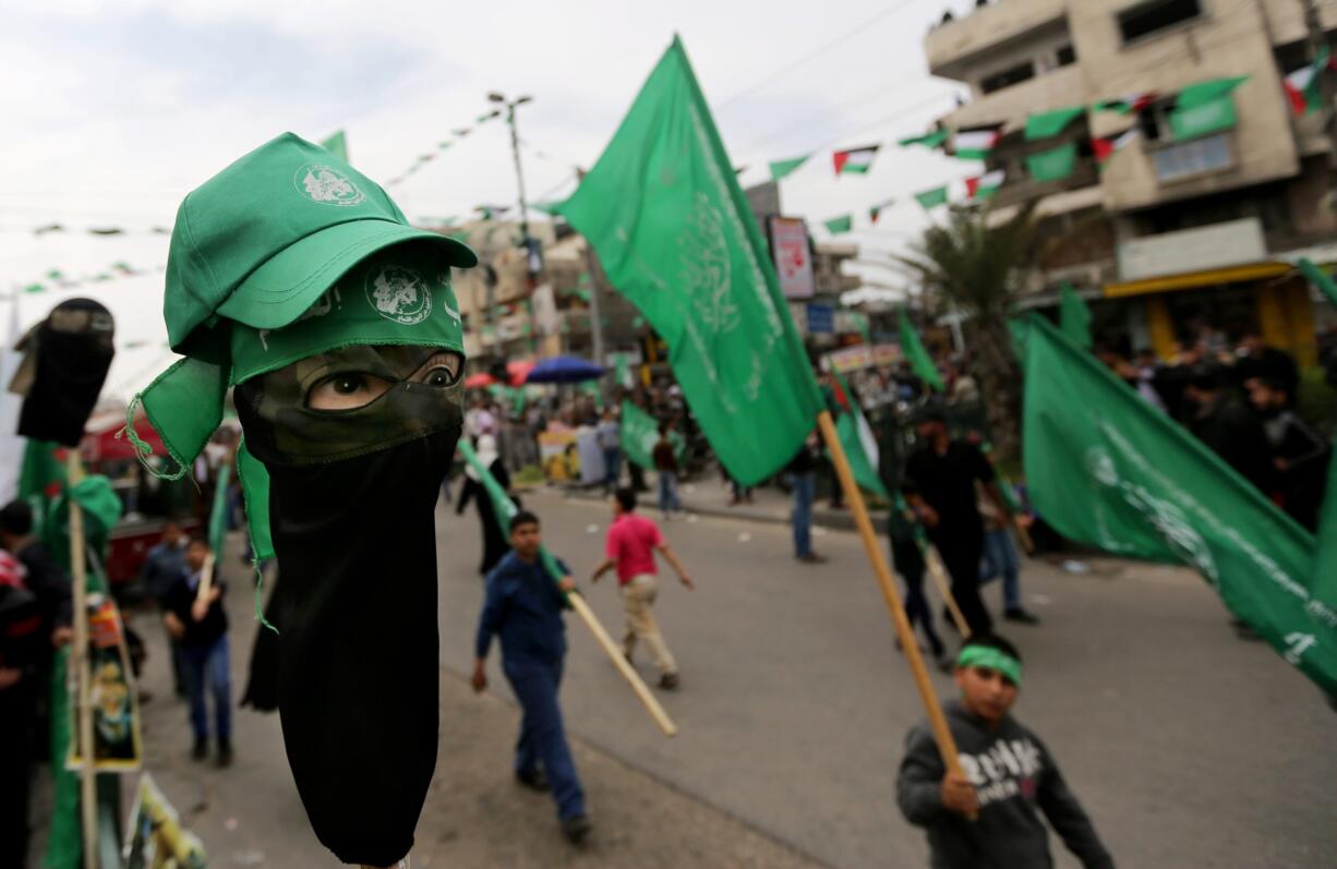 Hamas bandanas are displayed for sale Sunday, left, as tens of thousands of Hamas supporters attend a rally to commemorate the 10-year anniversary of the assassination of the group's spiritual leader.