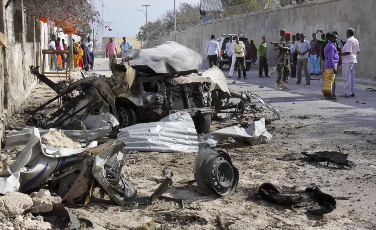 Somalis gather near the wreckage of one of the vehicles used Friday for a car bombing attack on the presidential palace in Mogadishu, Somalia.