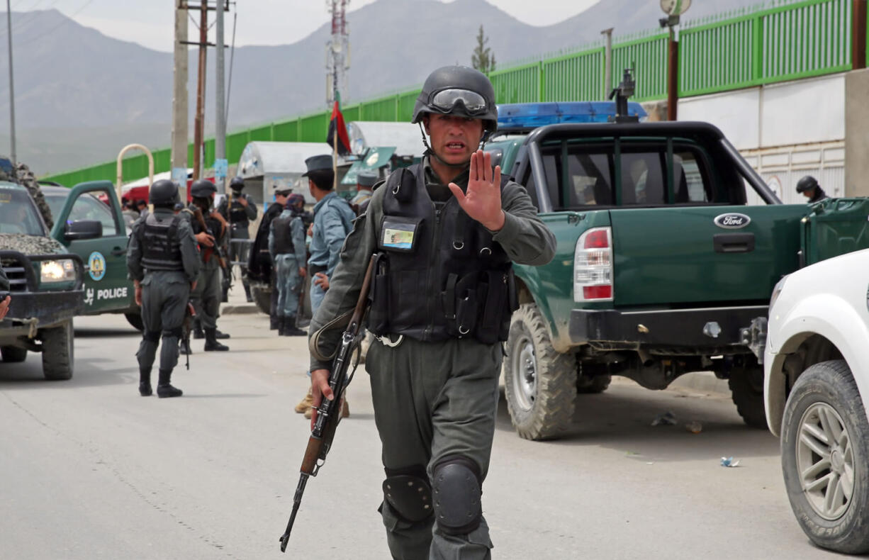 An Afghan policeman prevents journalists from approaching Cure International Hospital in Kabul, Afghanistan, on Thursday.