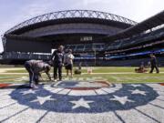 Groundskeepers finish prep work on the Seattle Mariners' field Monday, April 7, 2014, in Seattle. The Mariners, 4-2, open at home Tuesday against the Los Angeles Angels.