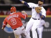 Seattle Mariners second baseman Robinson Cano, right, throws to first after forcing out Los Angeles Angels' John McDonald at second base in the fifth inning of a baseball game Wednesday, April 9, 2014, in Seattle. Mike Trout was safe at first.