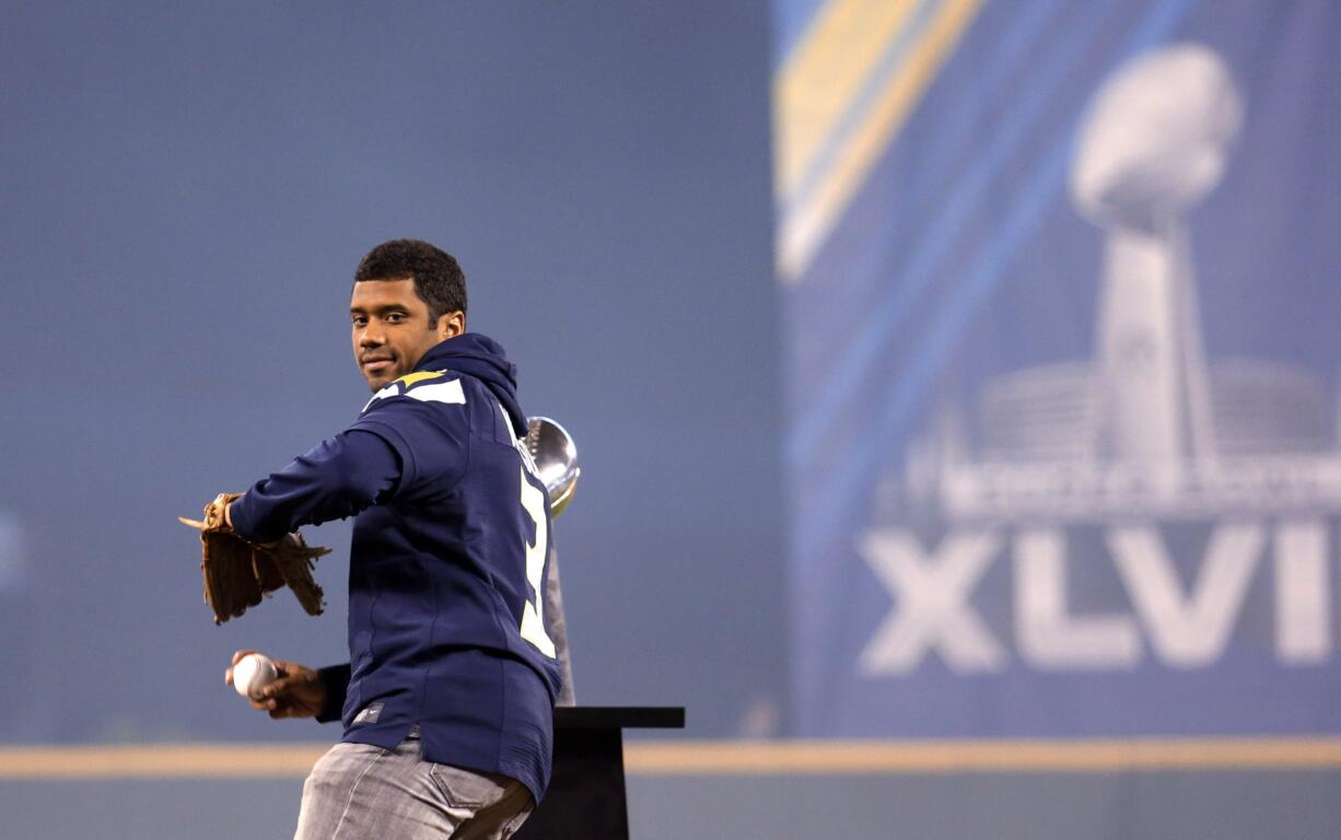 With the Lombardi Trophy as a backdrop, Seahawks quarterback Russell Wilson throws out the ceremonial first pitch at the Mariners home opener Tuesday.