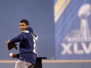 With the Lombardi Trophy as a backdrop, Seahawks quarterback Russell Wilson throws out the ceremonial first pitch at the Mariners home opener Tuesday.